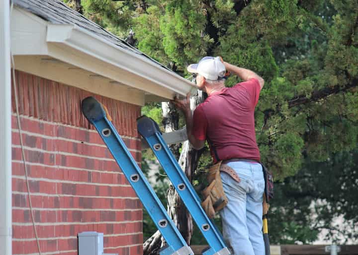 An emergency roof repair contractor standing on work ladder in Lithia Springs, Georgia